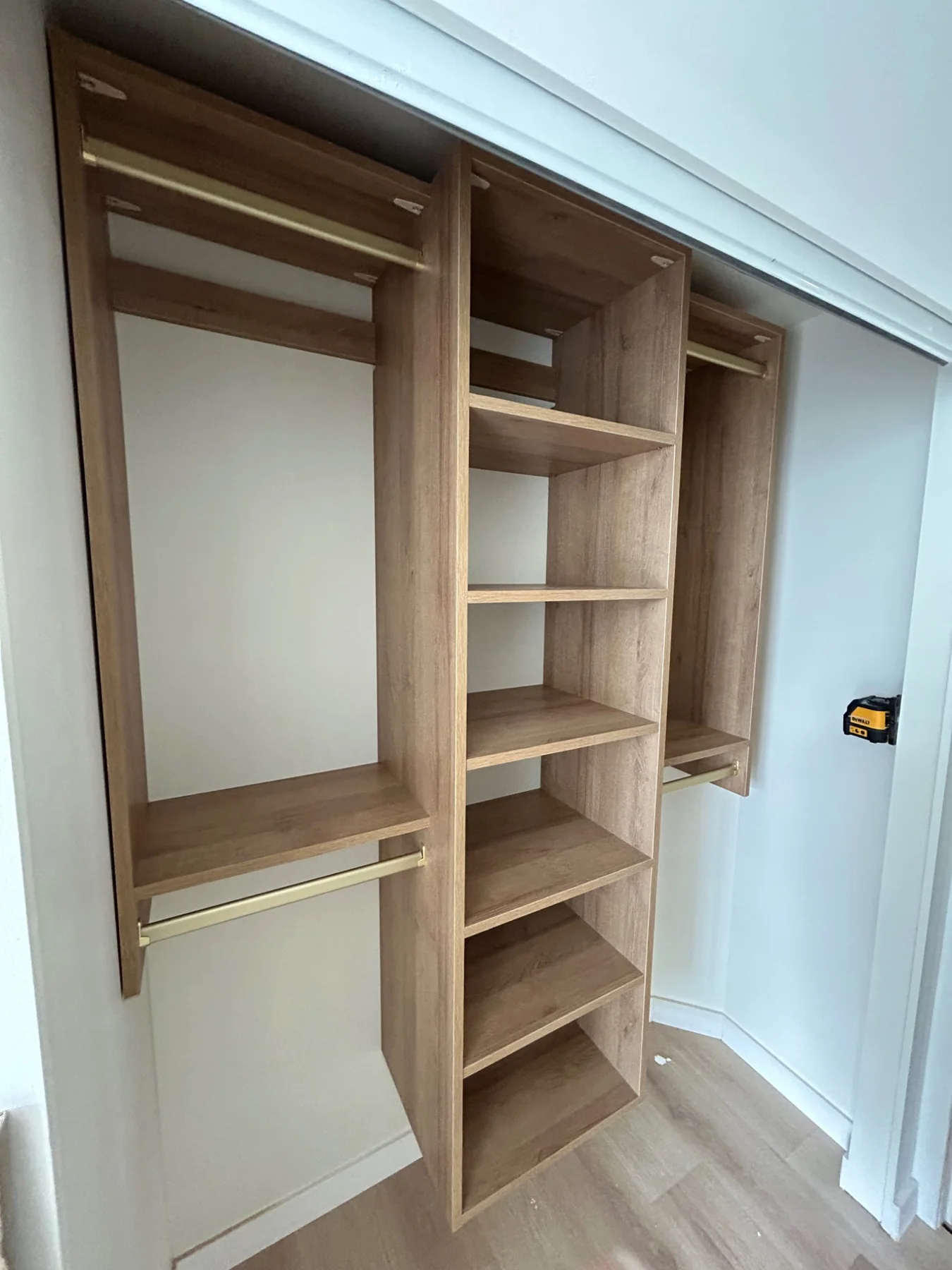 Warm oak-look custom closet with brass hanging rods