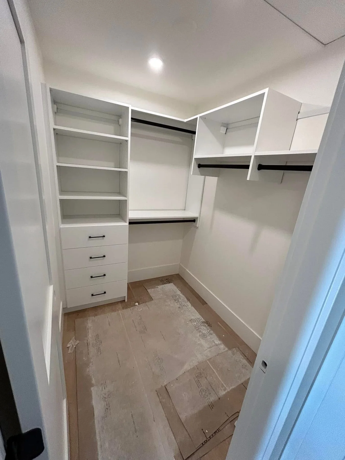 Bright white walk-in closet with black rods and drawers